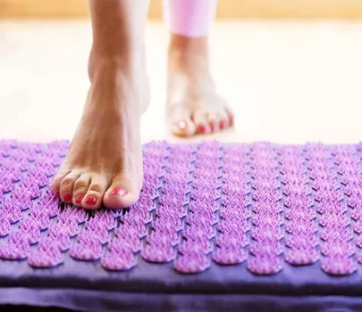 Frau benutzt Akupressurmatte für Fußmassagetherapie
