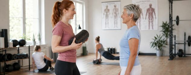 eine Faszientrainerin spricht mit einer Kundin in einem Trainingsraum