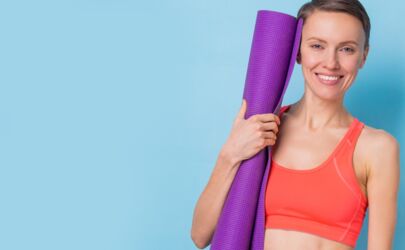 Porträt eines glücklichen Fitness-Mädchens, das eine Yoga-Übungsmatte hält